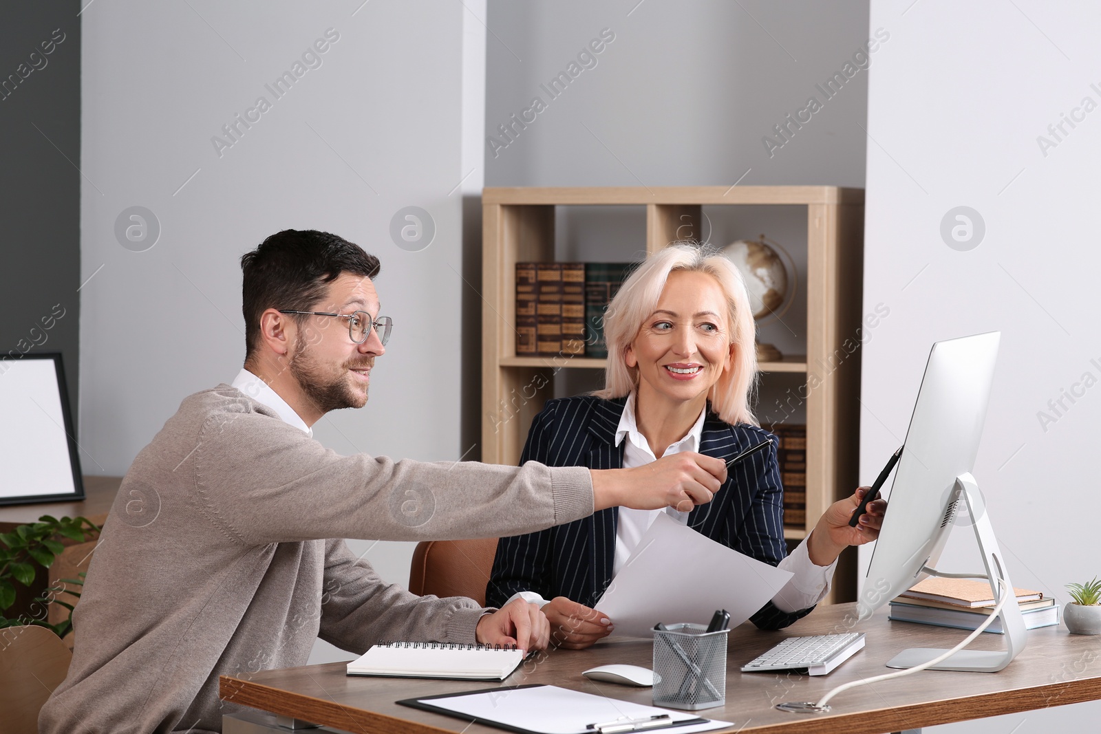 Photo of Boss and employee discussing work issues at wooden table in office