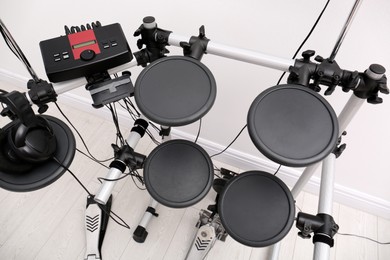 Photo of Modern electronic drum kit near white wall indoors, above view. Musical instrument