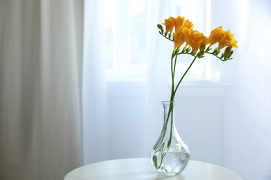 Photo of Beautiful yellow freesia flowers on table indoors. Space for text