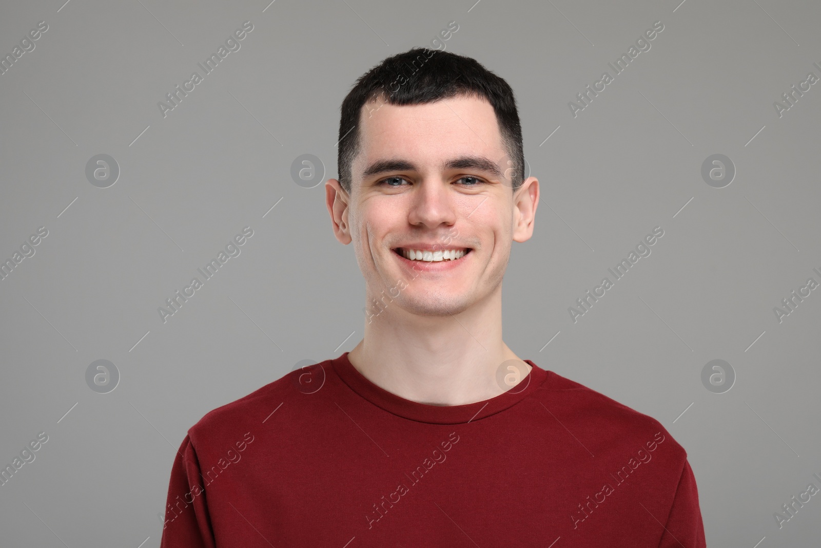 Photo of Handsome young man with clean teeth smiling on grey background