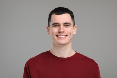 Photo of Handsome young man with clean teeth smiling on grey background
