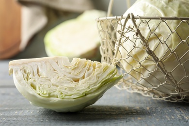 Photo of Whole and cut cabbages on grey wooden table, closeup