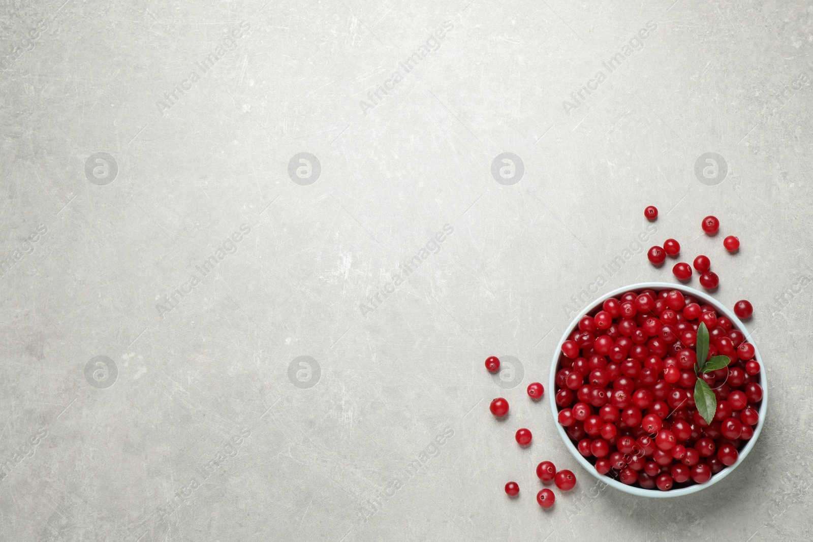 Photo of Tasty ripe cranberries on light grey table, flat lay. Space for text