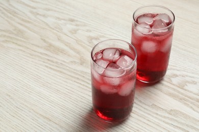 Photo of Glasses of delicious iced hibiscus tea on white wooden table, space for text