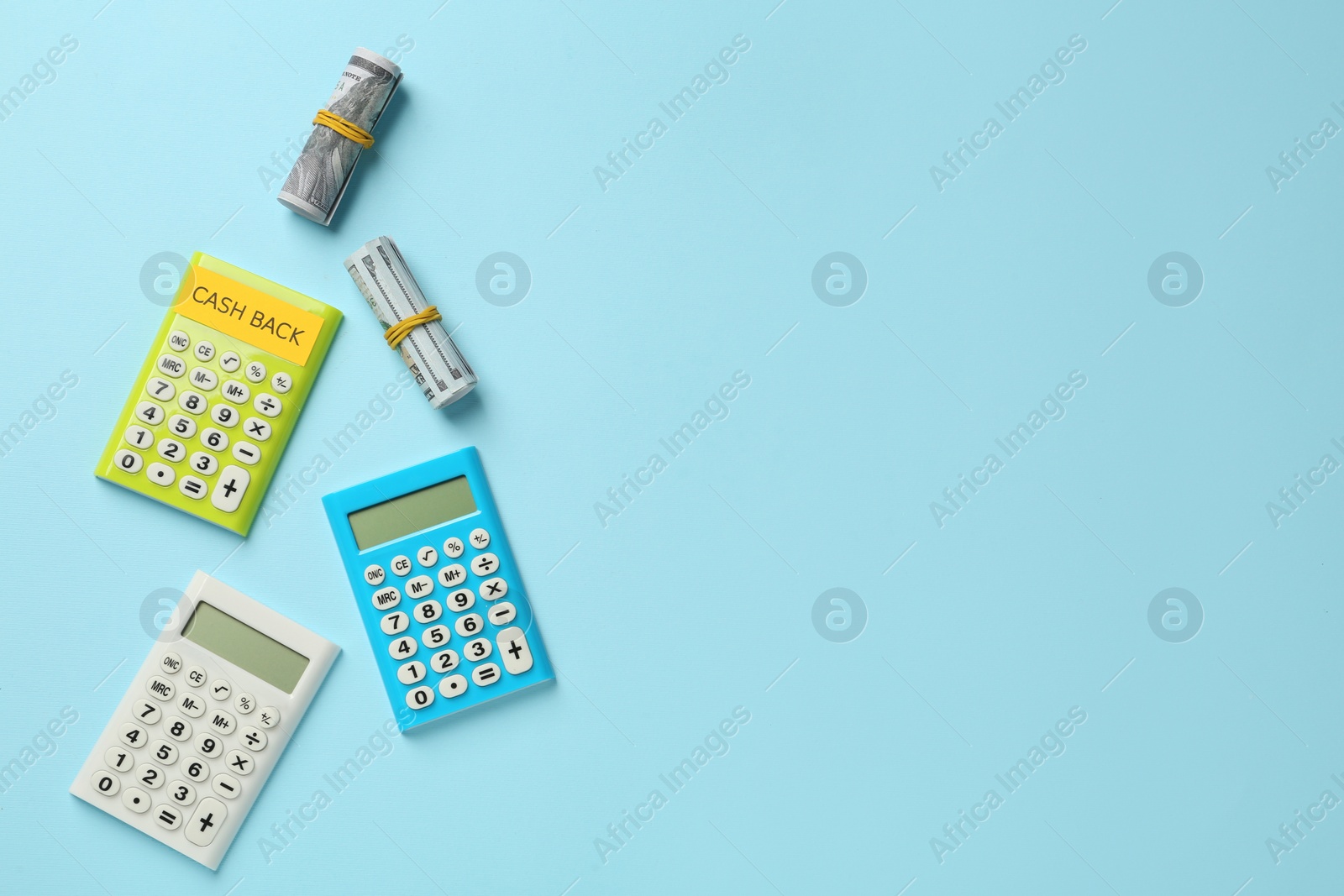 Photo of Different calculators and rolled dollar banknotes on light blue background, flat lay with space for text. Cashback concept