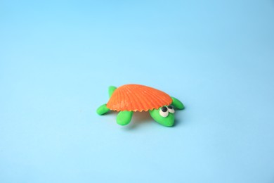 Photo of Turtle made from plasticine on light blue background. Children's handmade ideas
