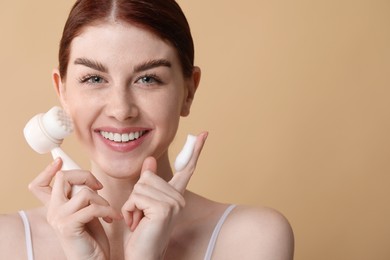 Photo of Washing face. Young woman with brush and cleansing foam on beige background, space for text