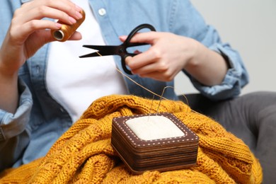 Woman sewing sweater, focus on pin cushion