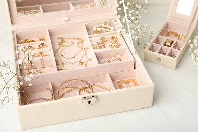 Photo of Jewelry boxes with different elegant bijouterie and flowers on white table