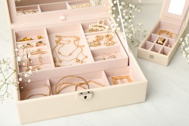 Jewelry boxes with different elegant bijouterie and flowers on white table