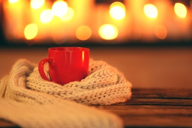 Cup of hot drink on wooden table against blurred background, space for text. Winter atmosphere