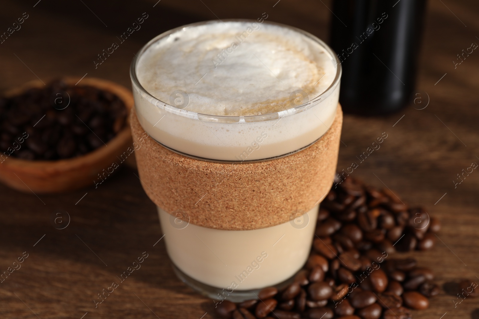 Photo of Bottle of delicious syrup, glass of coffee and beans on wooden table, closeup