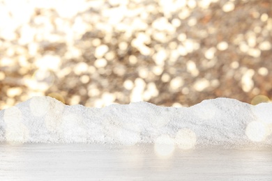 Image of Wooden surface with heap of snow and blurred Christmas lights on background, bokeh effect 