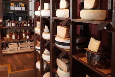 Different types of delicious cheeses on rack in store