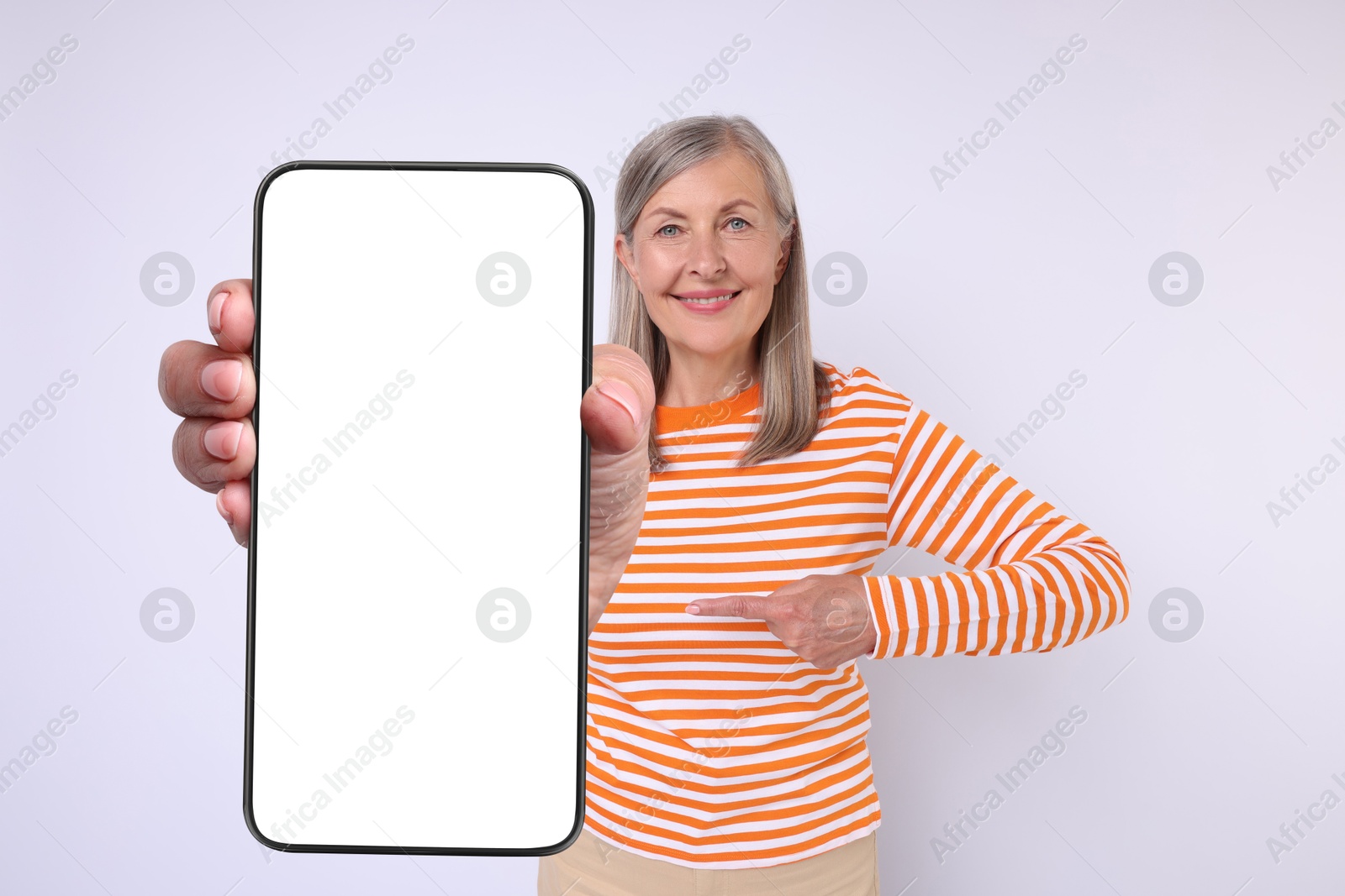 Image of Happy mature woman showing mobile phone with blank screen on white background. Mockup for design