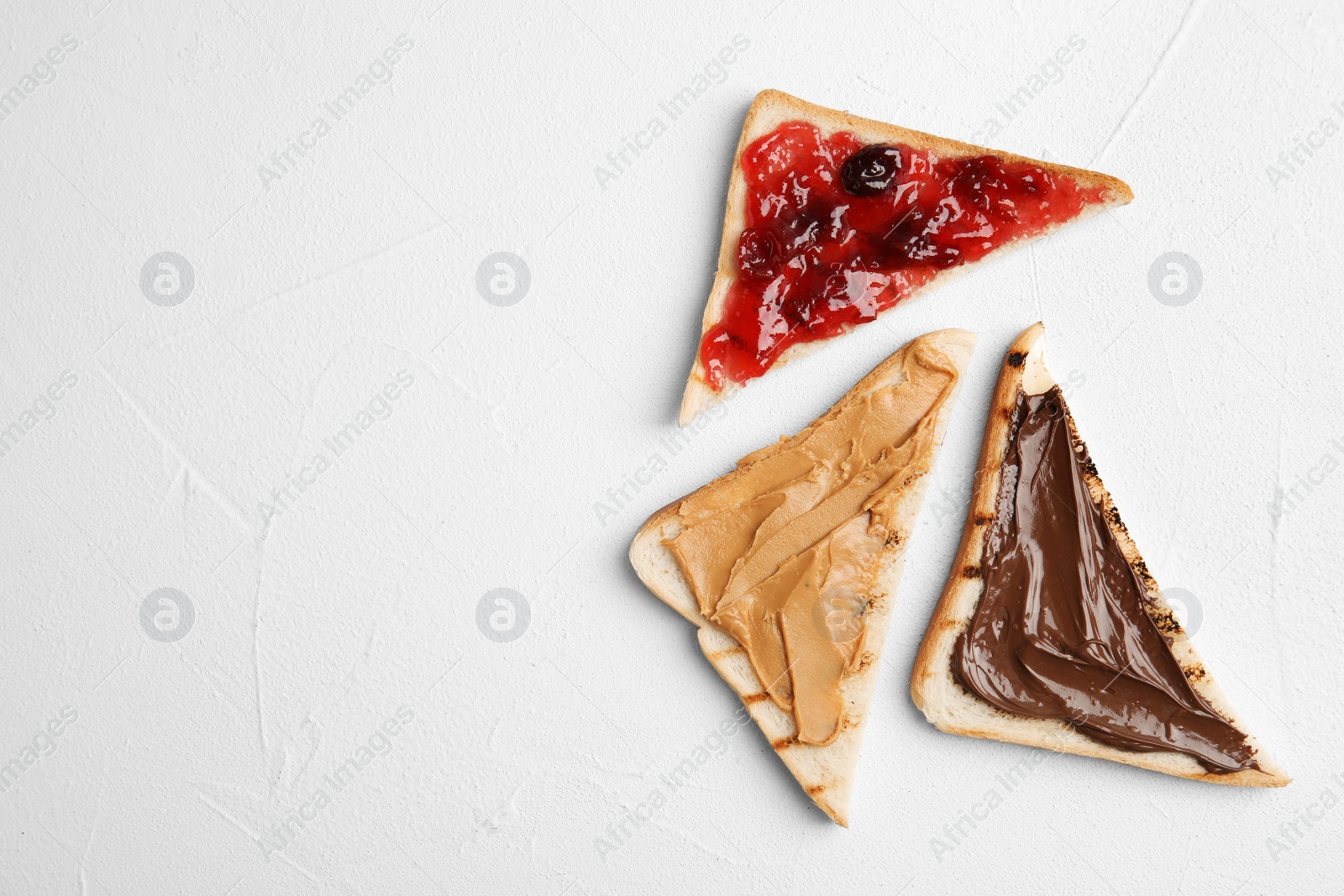 Photo of Slices of bread with different spreads on white table, flat lay. Space for text
