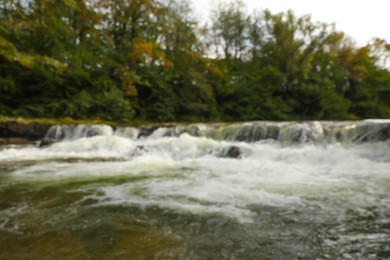 Blurred view of river with rapids near forest