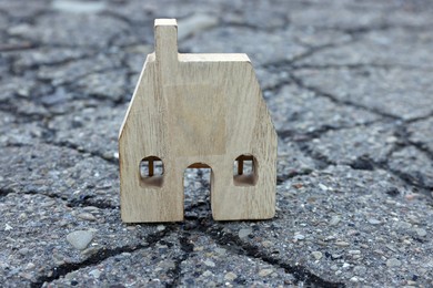 Photo of Wooden house model on cracked asphalt. Earthquake disaster