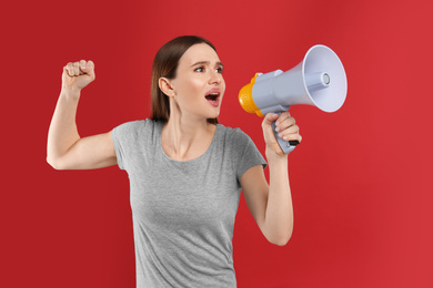 Photo of Emotional young woman with megaphone on red background