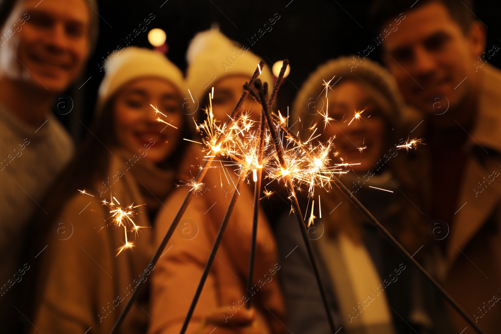 Photo of Group of people holding burning sparklers, focus on fireworks