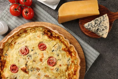 Photo of Delicious homemade cheese quiche and ingredients on gray table, flat lay