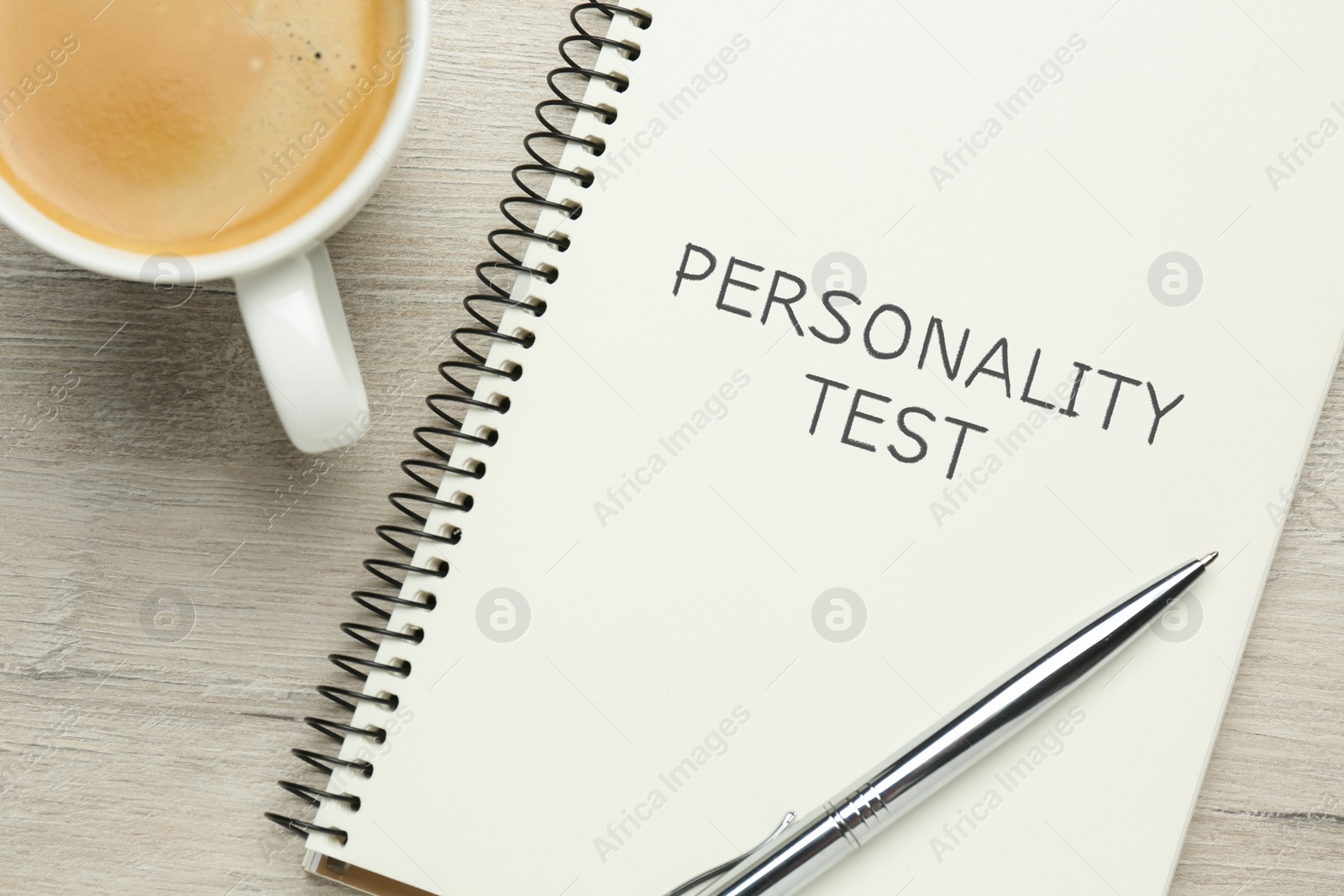 Image of Notebook with text Personality Test, cup of coffee and pen on white wooden table, flat lay