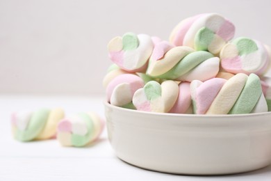 Photo of Bowl with colorful marshmallows on white table, closeup