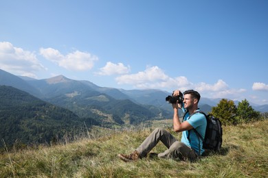 Professional photographer taking picture with modern camera in mountains. Space for text