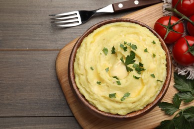 Bowl of freshly cooked mashed potatoes with parsley served on wooden table, flat lay. Space for text