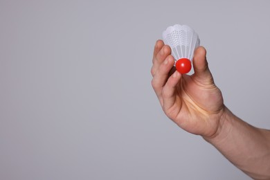 Photo of Man with badminton shuttlecock on light grey background, closeup. Space for text