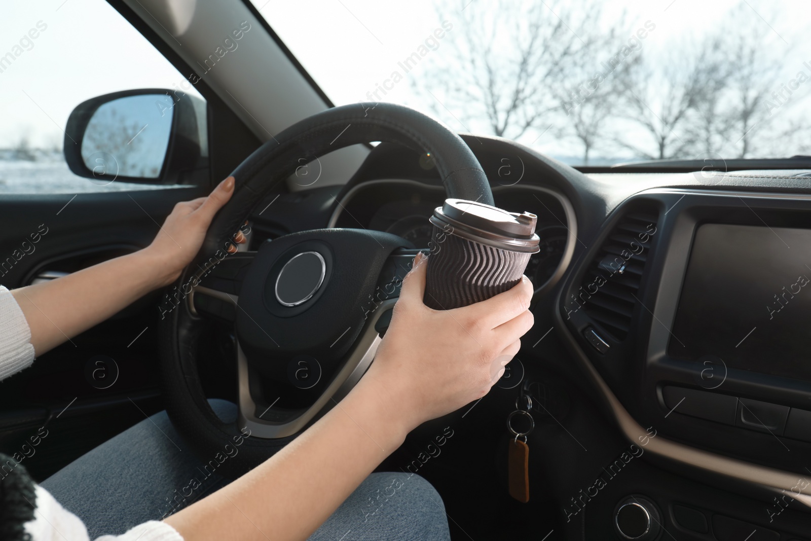 Photo of Young woman driving car and drinking coffee, closeup view. Cozy atmosphere