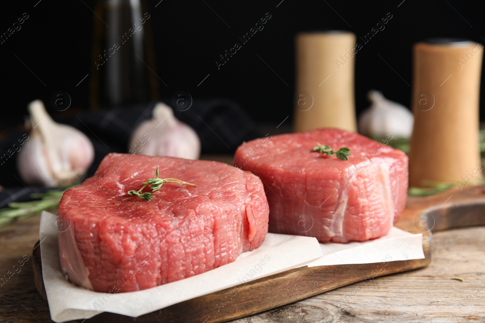 Photo of Fresh raw beef cut with thyme on wooden table, closeup
