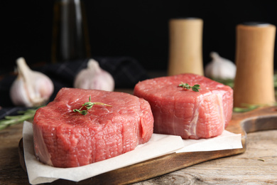 Photo of Fresh raw beef cut with thyme on wooden table, closeup