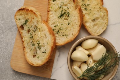 Tasty baguette with garlic and dill on light grey table, top view