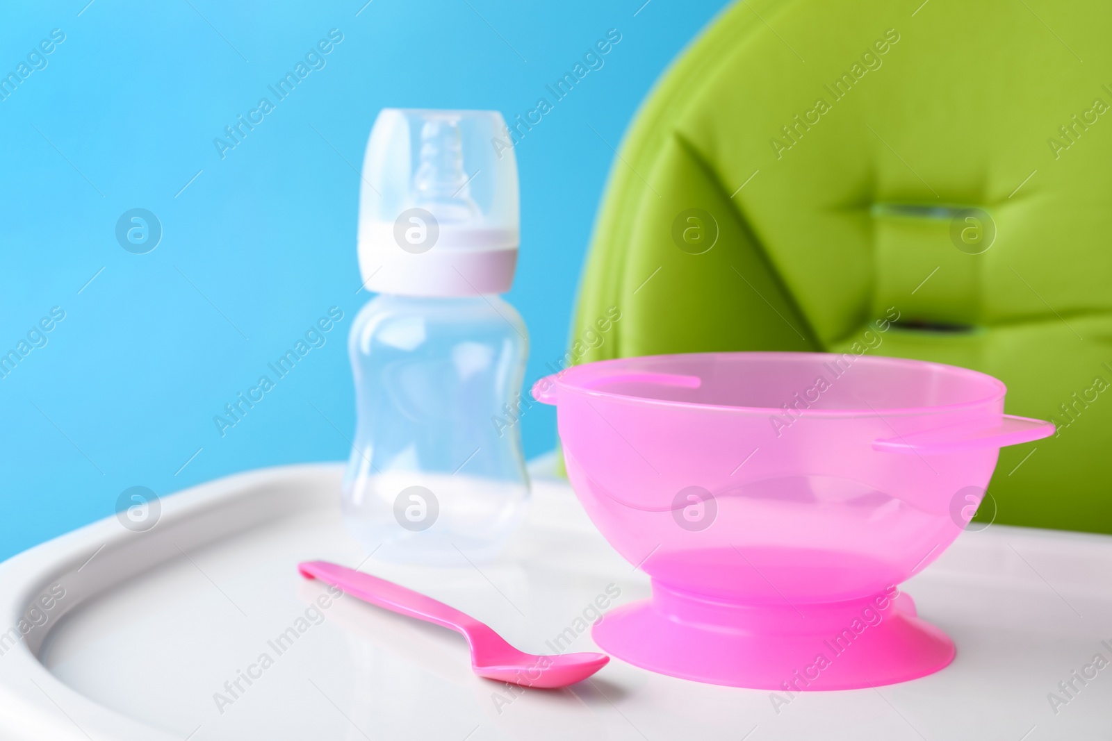 Photo of Set of plastic dishware on white feeding table. Serving baby food