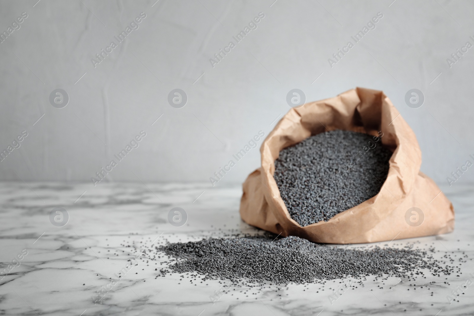 Photo of Poppy seeds with paper bag on table. Space for text