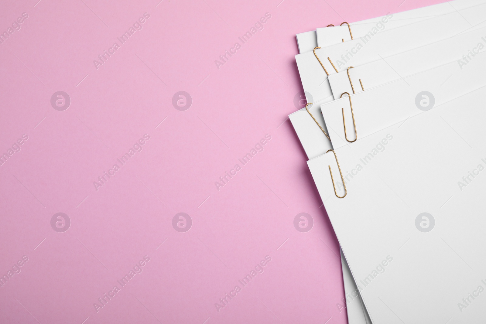 Photo of Sheets of paper with clips on pink background, top view. Space for text