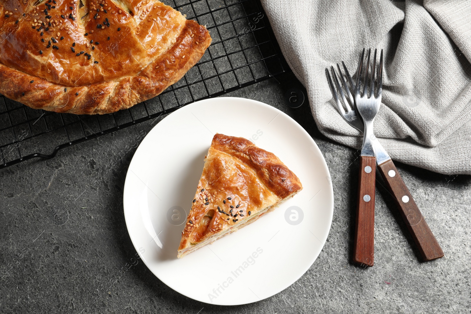 Photo of Piece of tasty homemade pie with filling served on grey table, flat lay