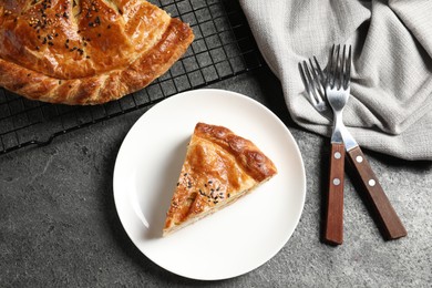 Photo of Piece of tasty homemade pie with filling served on grey table, flat lay