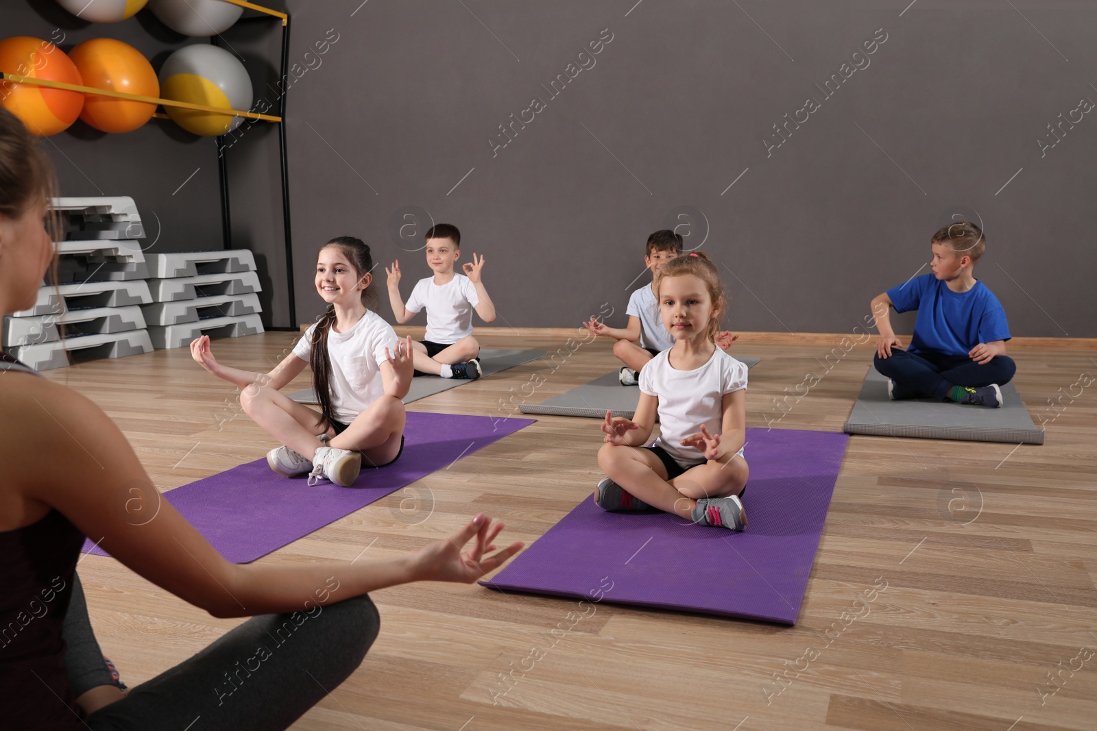 Photo of Cute little children and trainer doing physical exercise in school gym. Healthy lifestyle