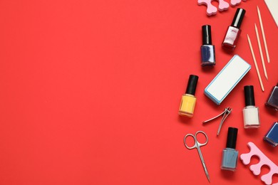 Photo of Nail polishes and set of pedicure tools on red background, flat lay. Space for text