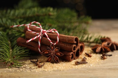Photo of Different spices and fir branches on wooden table, closeup