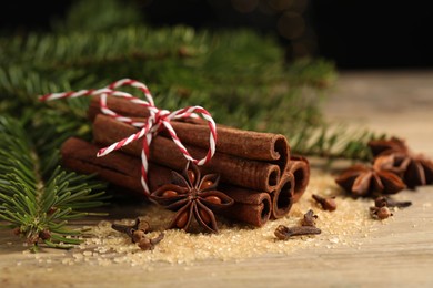 Different spices and fir branches on wooden table, closeup