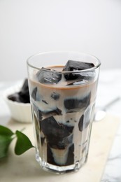 Photo of Glass of milk with grass jelly on table, closeup