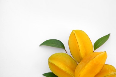 Photo of Delicious ripe carambolas with green leaves on white background, top view