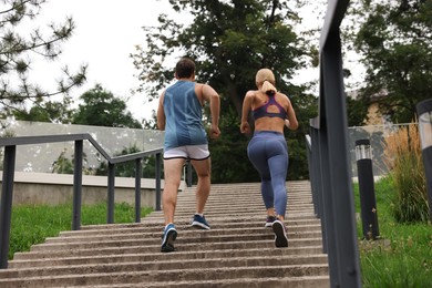 Photo of Healthy lifestyle. Couple running up stairs outdoors, back view