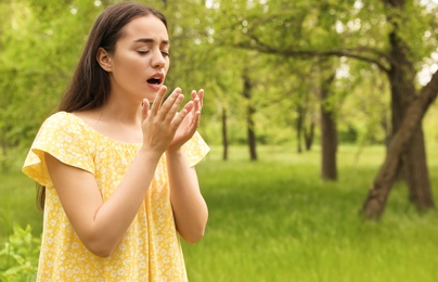 Photo of Young woman suffering from seasonal allergy outdoors, space for text