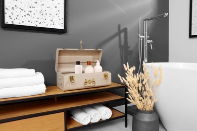 Stylish bathroom interior with ceramic tub, towels and cosmetic products