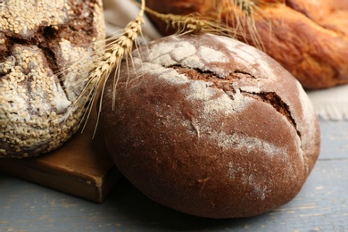 Photo of Loaves of delicious fresh bread on grey wooden table, closeup