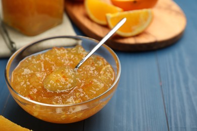 Delicious orange marmalade in bowl on blue wooden table. Space for text